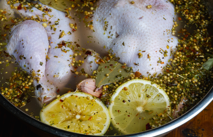 Uncooked chicken in liquid/brine with lemons and herbs.