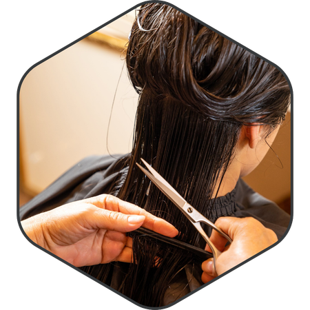 Cosmetology student cutting hair with scissors.
