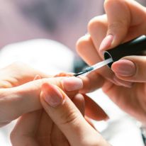Nail Technician adding polish to nails.