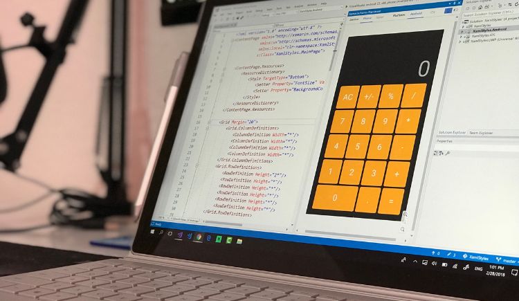 A laptop displaying a calculator app design alongside its code, showing the interface layout and orange calculator buttons.