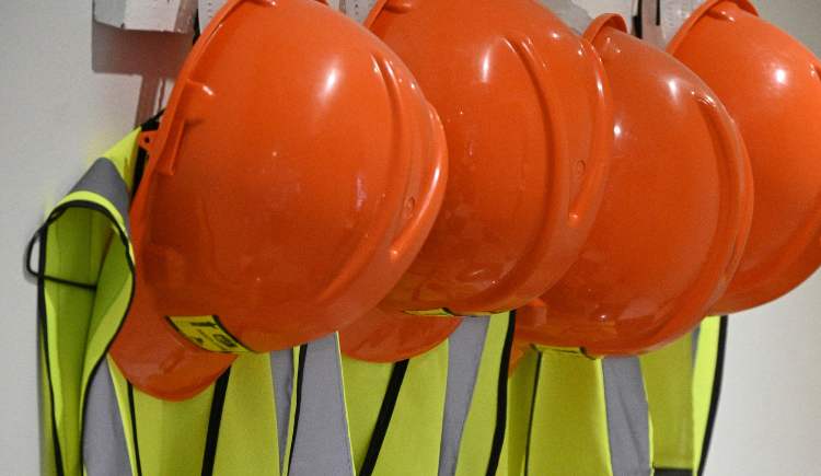 orange work hats hanging on the wall with yellow work vests