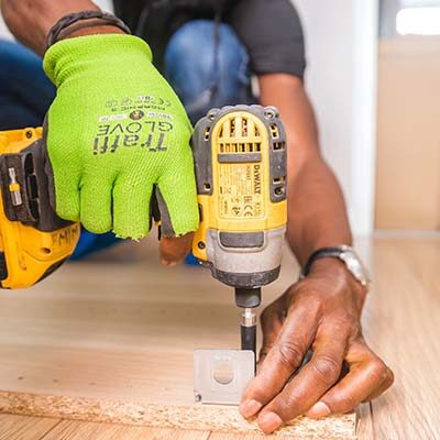 Construction worker screwing a nail in with a drill.