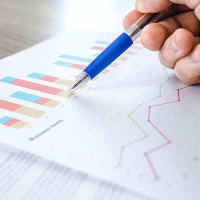 A business report with charts being reviewed and annotated with a pen
