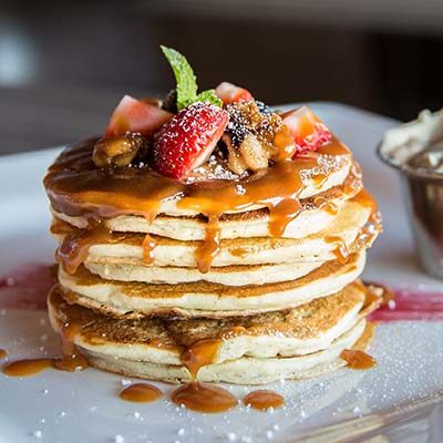 A stack of pancakes with syrup and fruit