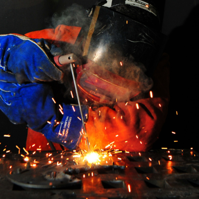 A welder creating a metal weld with a welding torch